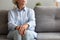 Unhappy depressed senior woman sit alone on sofa, closeup view