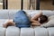 Unhappy depressed young woman sleeping on couch at home