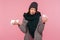 Unhappy frustrated sick woman in warm scarf and hat holding medicine and napkin in hands, stressed because of health problems