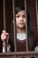 Unhappy girl standing behind bars