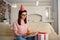 An unhappy girl wearing a hat on her birthday with a cake with c