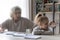 Unhappy grandmother and small granddaughter have fight doing homework