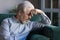 Unhappy lonely grey haired mature man sitting on couch