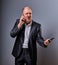 Unhappy loud crying angry business man talking on mobile phone very emotional in office suit on grey background. Closeup