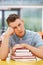 Unhappy Male Student Studying In Classroom With Books