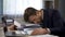 Unhappy overworked male manager lying on pile of folders at workplace, tiredness