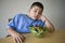 Unhappy preadolescent Boy Sitting At Desk With Salad