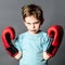 Unhappy preschooler with red hair showing his boxing gloves