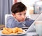 Unhappy preteen boy sitting near laptop at home table