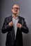 Unhappy serious fun bald business man getting dressed the suit in eyeglasses on grey background. Closeup