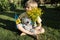 unhappy seven-year-old boy sits on grass with teddy bear, Ukrainian flag, bouquet of yellow flowers