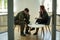 Unhappy soldier in green uniform and psychotherapist during consultation in the office