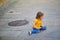 Unhappy and stubborn toddler girl sitting on the floor outdoors