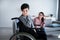 Unhappy teen boy in wheelchair having conflict with his mother, listening to her scolding at home. Relationship problems