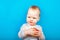 Unhappy thoughtful child with apple on blue background. Pensive baby and first feeding. Complementary feeding of child, nutritiona