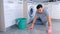 Unhappy tired man in rubber gloves washes the floor in the kitchen and looks at the camera at the end.