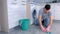 Unhappy tired man in rubber gloves washes the floor in the kitchen and looks at the camera at the end.