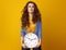 Unhappy trendy woman isolated on yellow with clock