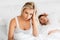 Unhappy woman in bed with snoring sleeping man