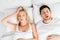 Unhappy woman in bed with snoring sleeping man