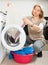 Unhappy woman cheking white clothes near washing machine