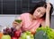 Unhappy woman drinking vegetable juice in kitchen