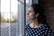 Unhappy woman look in window feeling worried