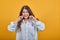 Unhappy woman in shirt closed ears with fingers, squeezing face, disappointed