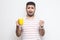 Unhappy worry sick young adult man in white t-shirt standing and holding yellow cup with white napkin, drink hot tea, has flu