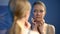 Unhappy young lady looking in mirror reflection, upset with skin imperfection