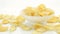 Unhealthy Harmful food, yellow delicious Potato ribbed crispy chips randomly lying in bowl and on a white table background, close-