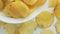 Unhealthy Harmful food, yellow delicious Potato ribbed crispy chips randomly lying in bowl and on a white table background, close-