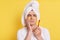 Unhealthy man wrapped towel on head doing morning cosmetology procedures, feels pain after brushing teeth, posing with patches