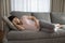 Unhealthy pregnant woman lying on sofa having pain