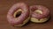 Unhealthy but tempting sugary dessert - two yummy and delicious chocolate donuts with colored sprinkles on shinny wood table in