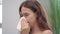 Unhealthy young girl with runny nose while cold disease sneezing in handkerchief