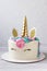 Unicorn cake with a golden horn and colored mane. Cream cake with meringues