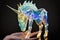 Unicorn model on hand in iridescent holographic isolated on black background.