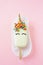 Unicorn popsicle with closed eyes on a pink background. Glazed with white chocolate. ice cream