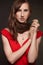 Unideal brunette young woman with untidy hairstyle and with gentle makeup in the red short dress posing at the black