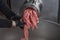 Unidentifiable butcher holding tray full of minced raw red meat leaving machine in food processing plant