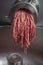 Unidentifiable butcher holding tray full of minced raw red meat leaving machine in food processing plant