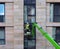 Unidentifiable construction worker in a green aerial work platform on a large housing urban construction site