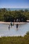 Unidentifiable people wade across the lagoon to get to Tigertail Beach on Marco Island