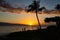 Unidentifiable people walking at sunsetwith a view of Lanai from Baby Beach on the island of Maui.