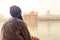 Unidentifiable Punjabi Sikh pilgrim devotee sitting by the holy pool and meditating in front of Golden Temple