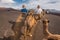 Unidentifiable tourist riding Camels in volcanic landscape in Timanfaya national park, Lanzarote, Canary islands, Spain.