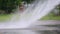 Unidentified asian worker using a powerful hose sprayer from a tanker truck to wash the road