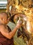 Unidentified Burmese monk is cleaning Buddha statue with the golden paper at Mahamuni Buddha temple, August