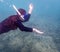An Unidentified Female Snorkeler In Cloudy Water On A Shallow Reef, Captured Underwater